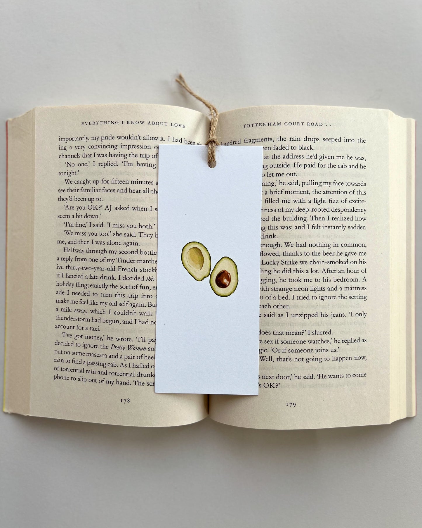 Open book with a bookmark featuring avocado illustrations on a light gray background