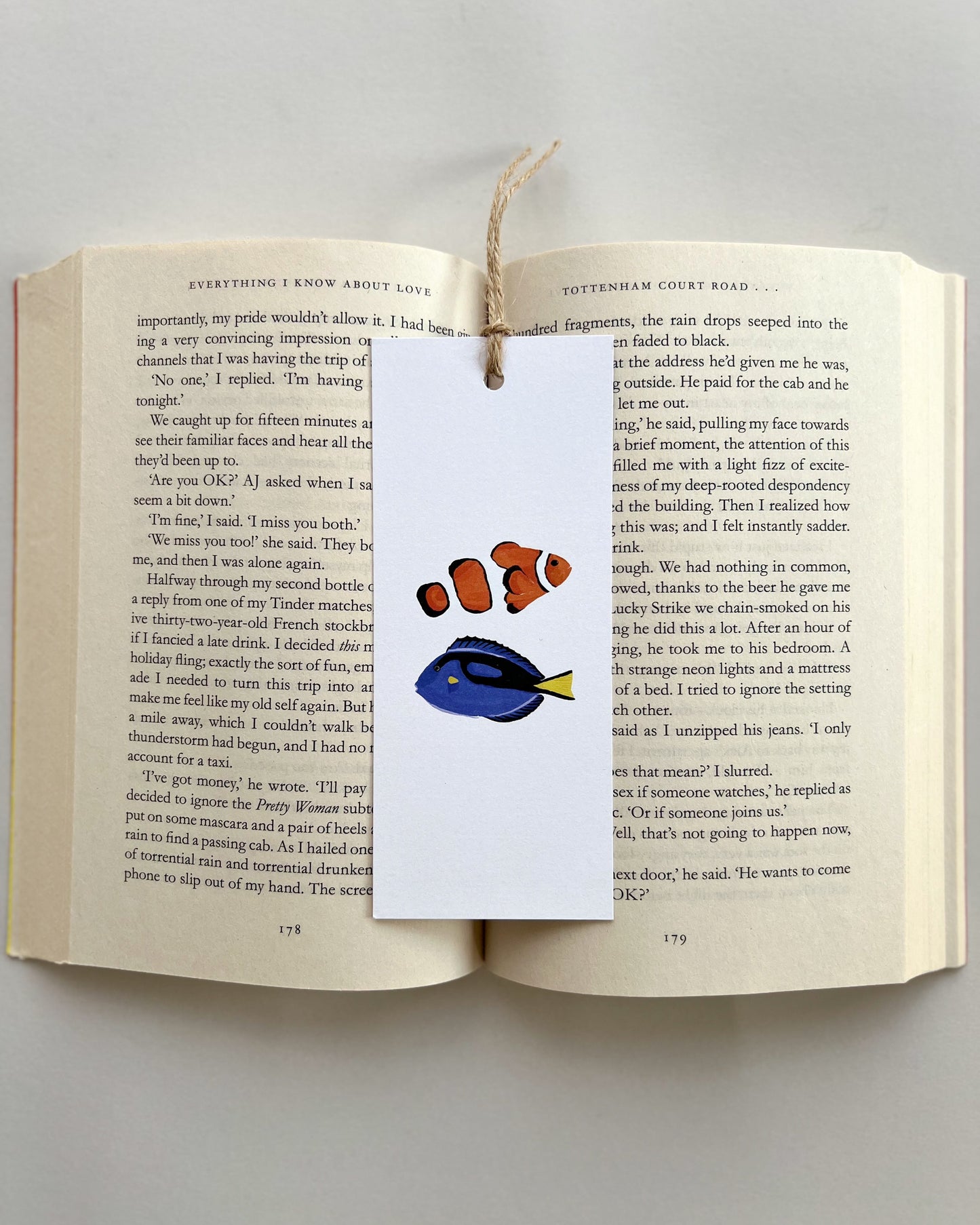 Open book with a bookmark featuring nemo and dory on a plain background