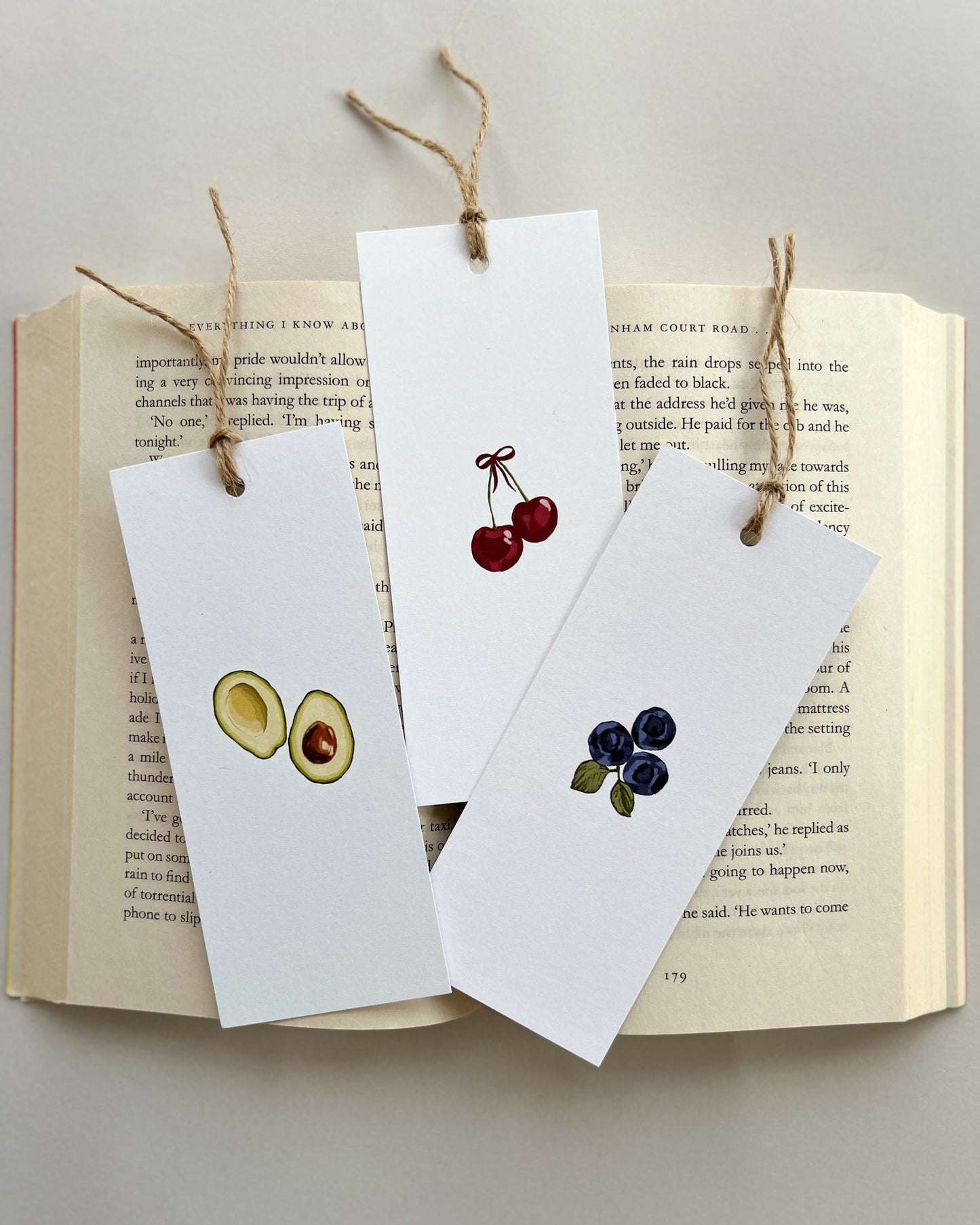 Three white bookmarks with fruit illustrations on an open book.