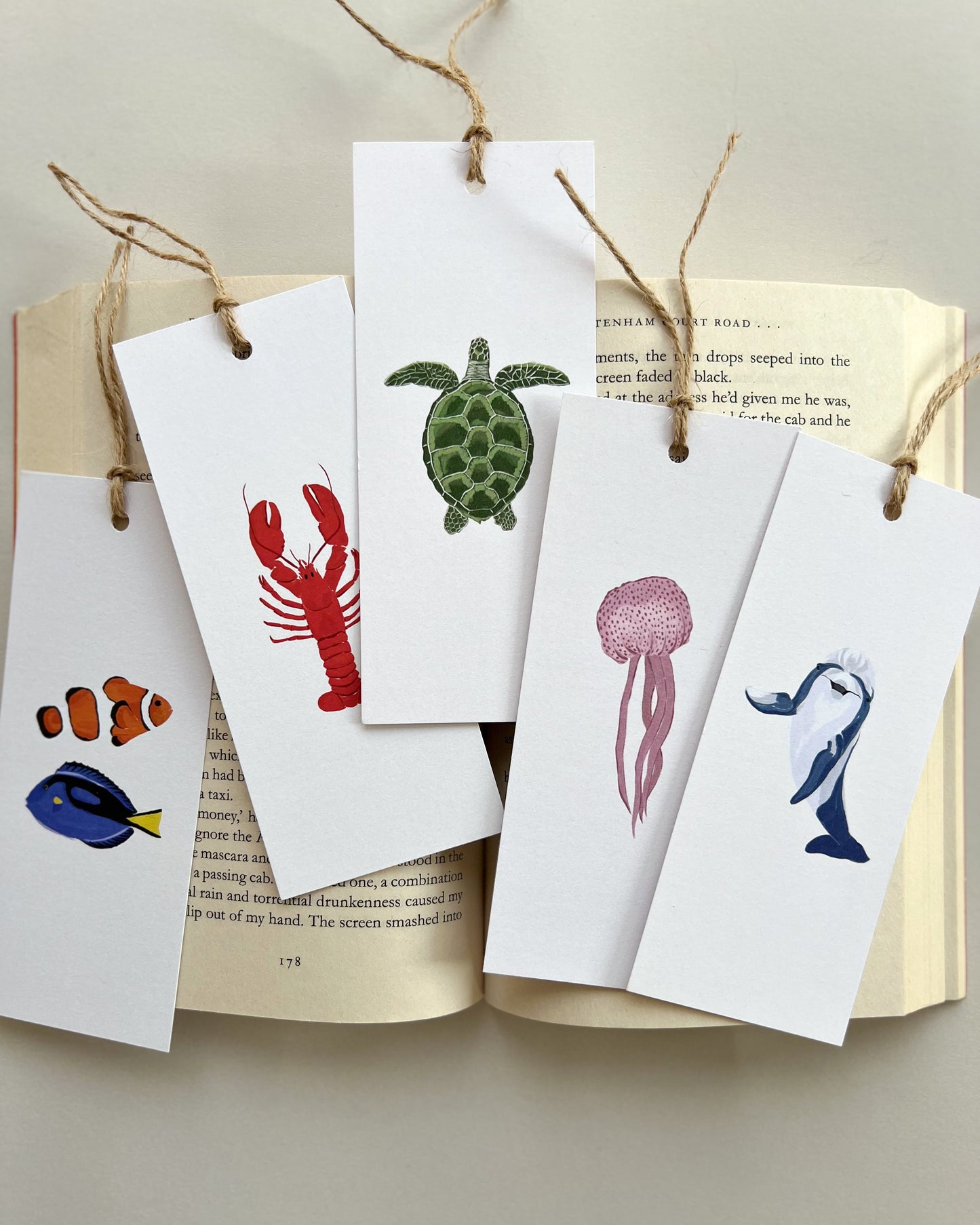 Set of animal-themed bookmarks hanging on a string with a beige background.