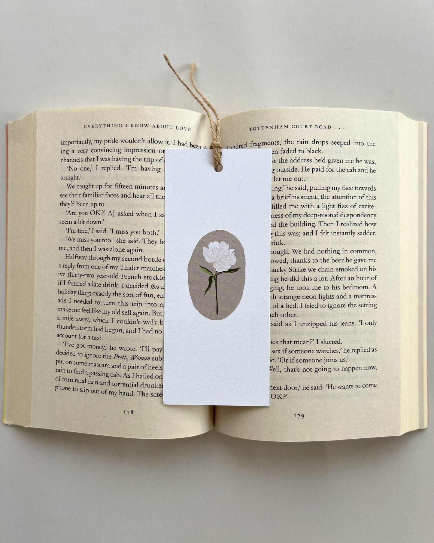Open book with a bookmark featuring a white rose flower illustration on a light gray background