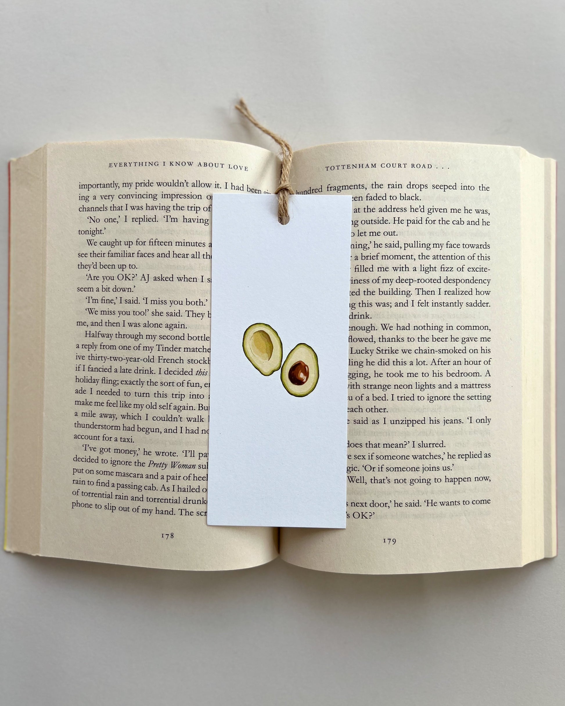 Open book with a bookmark featuring avocado illustrations on a light gray background