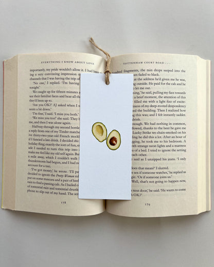 Open book with a bookmark featuring avocado illustrations on a light gray background