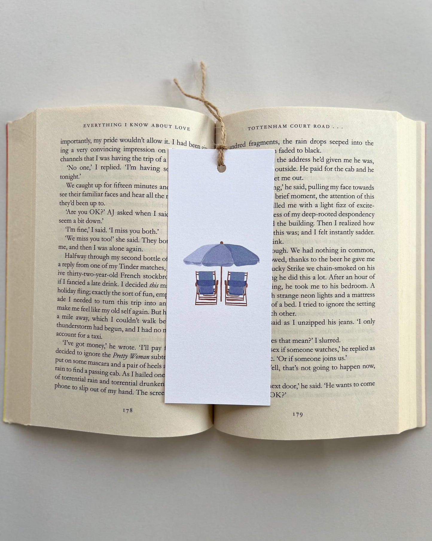 Open book with a bookmark featuring beach chairs and an umbrella on a white background