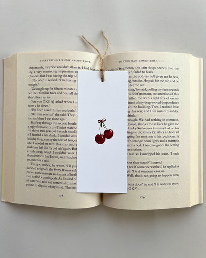 Open book with a cherry bookmark on a gray background