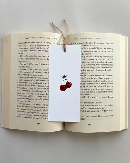 Open book with a cherry bookmark on a gray background