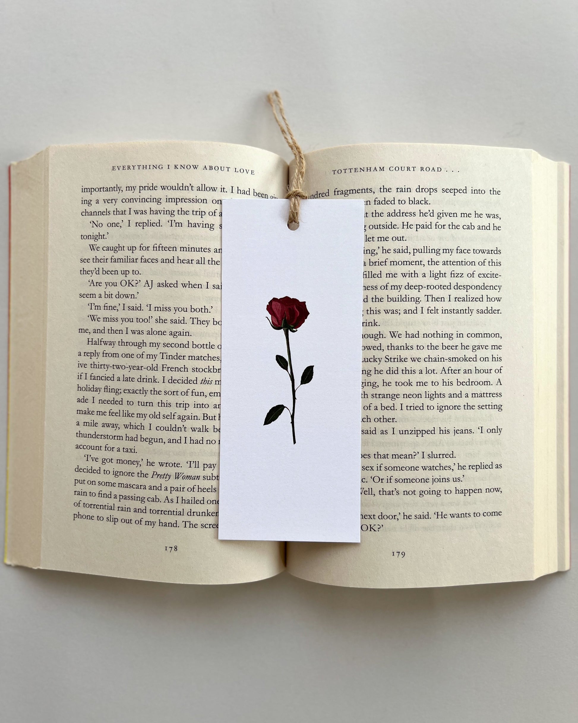 Open book with a bookmark featuring a red rose illustration on a white background