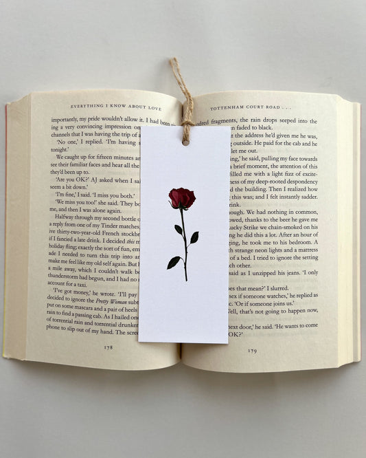 Open book with a bookmark featuring a red rose illustration on a white background