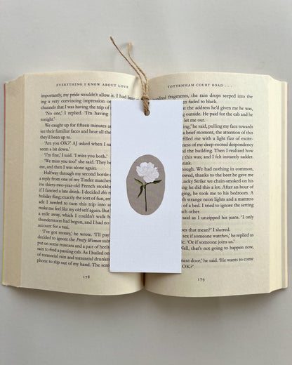 Open book with a bookmark featuring a white rose flower illustration on a light gray background